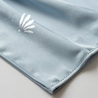 Emblème Belqia au coin du foulard, liquid jersey bleu poudré